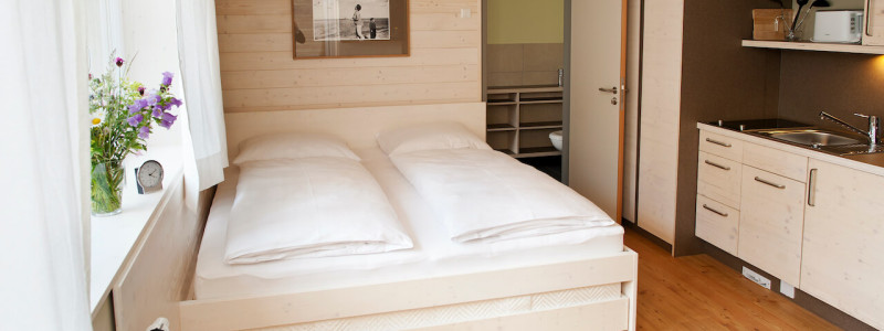 nachhaltige unterkunft familienhotel weimar urlaub in deuschland in der stadt oekologisches holzhaus stadturlaub staedtereise mit kindern mit grosseltern apartments umweltbewusstes reisen kleines zimmer bett kuechenzeile