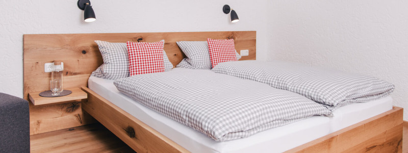 nachhaltige unterkunft apartments goldvogel fischen allgaeu urlaub in den bergen biologisch ökologisch regional hausgemacht architekt innenarchitekt suite betten frisch bezogen mit karierter bettwaesche schlafzimmer