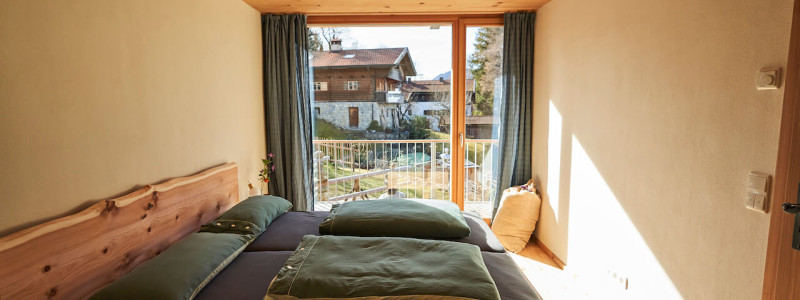 stadtalm toelzer land bad toelz urlaub in deutschland in der natur in bayern in den bergen auf dem land im gruenen nachhaltige oekologische unterkunft holz lehm bienen lamas kubische bauweise alpinarchitektur schlafzimmer zirbenholz erholsamer schlaf blick nach draussen