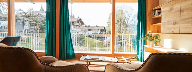 stadtalm toelzer land bad toelz urlaub in deutschland voralpenland in der natur in bayern in den bergen auf dem land im gruenen nachhaltige oekologische unterkunft holz lehm bienen lamas kubische bauweise alpinarchitektur ferienwohnung isarflimmern karwendelrauschen ledersessel blick in den garten