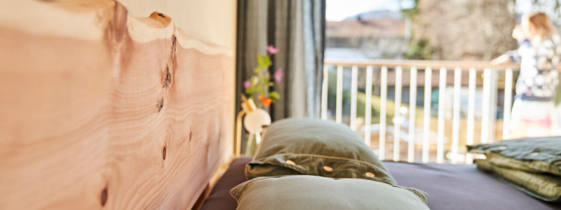 stadtalm toelzer land bad toelz urlaub in deutschland in der natur in bayern in den bergen auf dem land im gruenen nachhaltige oekologische unterkunft holz lehm bienen lamas kubische bauweise alpinarchitektur schlafzimmer zirbenholz blick nach draußen detail kopfkissen