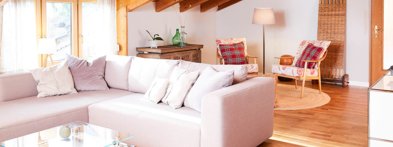 nachhaltige unterkunft urlaub am wasser in deutschland chiemsee alpen uebersee ferienapartment modern traditionell bienen imkerei insektenfreundlicher garten upcycling sofa mit sesseln im hintergrund