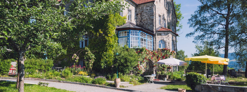 villa breitenberg bayerischer wald nachhaltige unterkunft boutiquie hotel ferienwohnung natur berge ruhe biologische kueche kultur seminare yoga retreats hochzeiten frontansicht gelber sonnenschirm