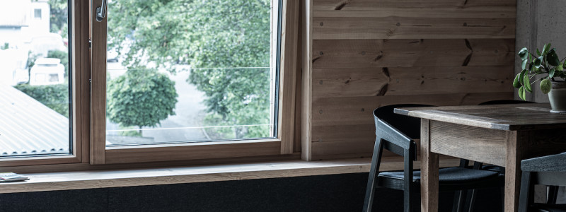 weingut idler bio appartment biologisches weingut remstal weinregion mondholz zirbenholz natuerliche materialien moderne architektur weinberge wandern radfahren kanufahren kultur weinarchitektur urlaubsarchitektur innenaufnahme blick fenster tisch stuhl